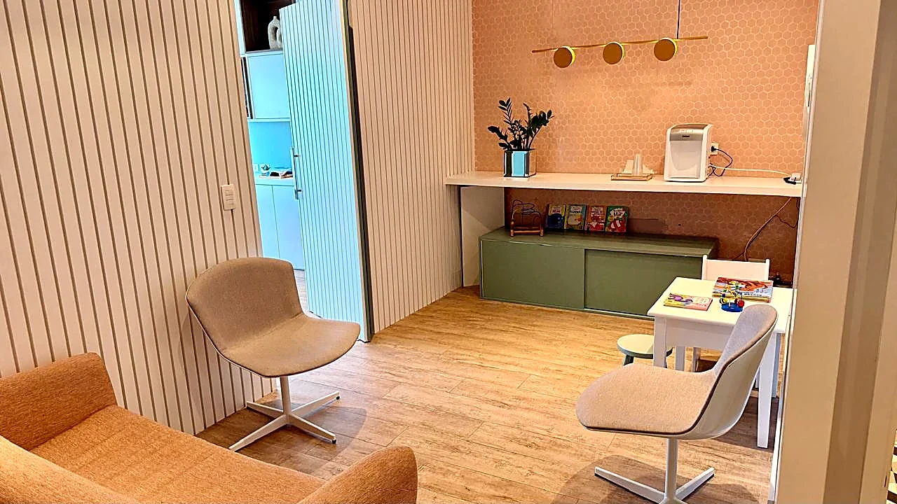 Ambiente infantil do consultório com mesa, brinquedos e poltronas